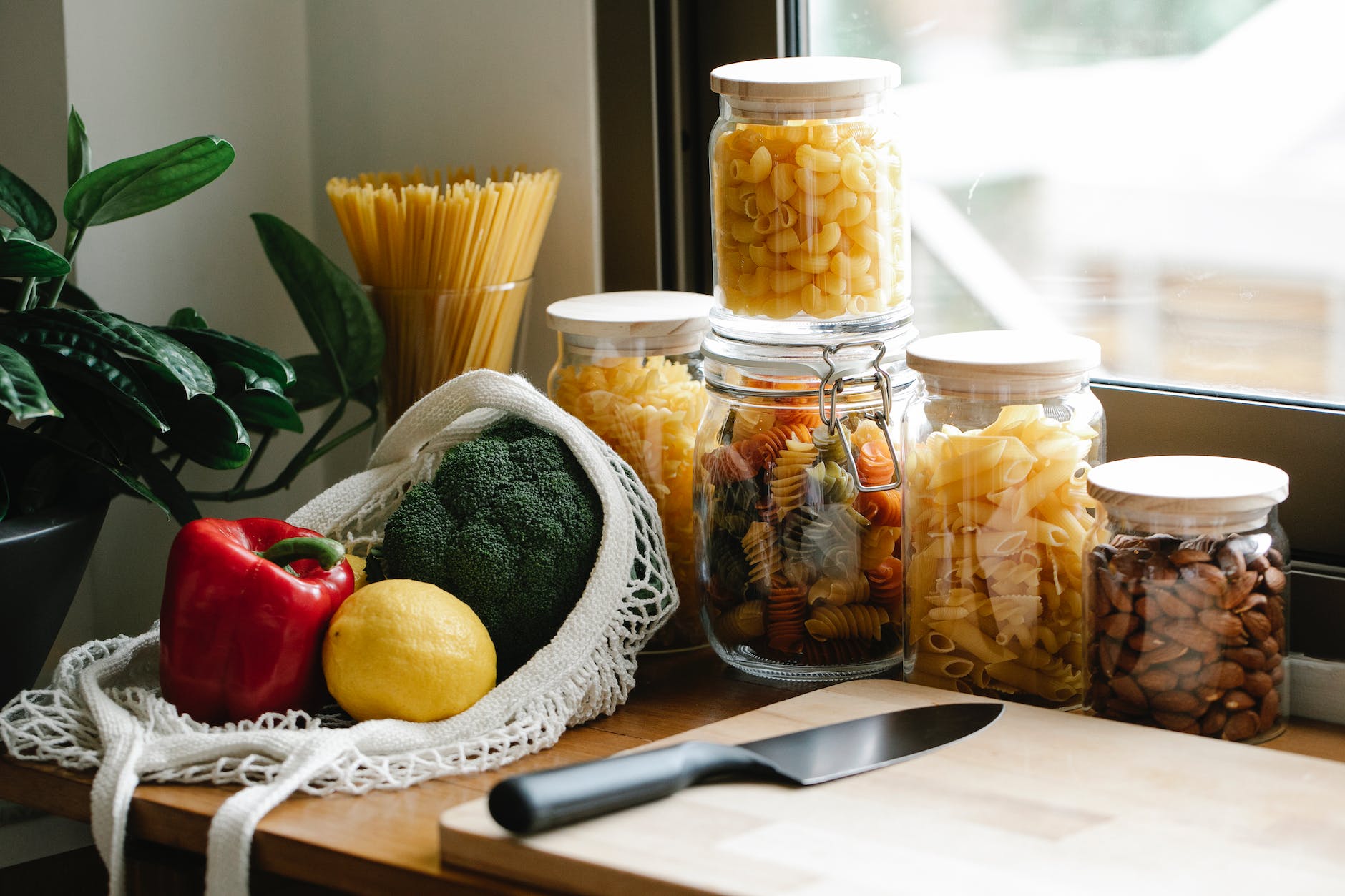 assorted vegetables placed on counter near jars with pasta