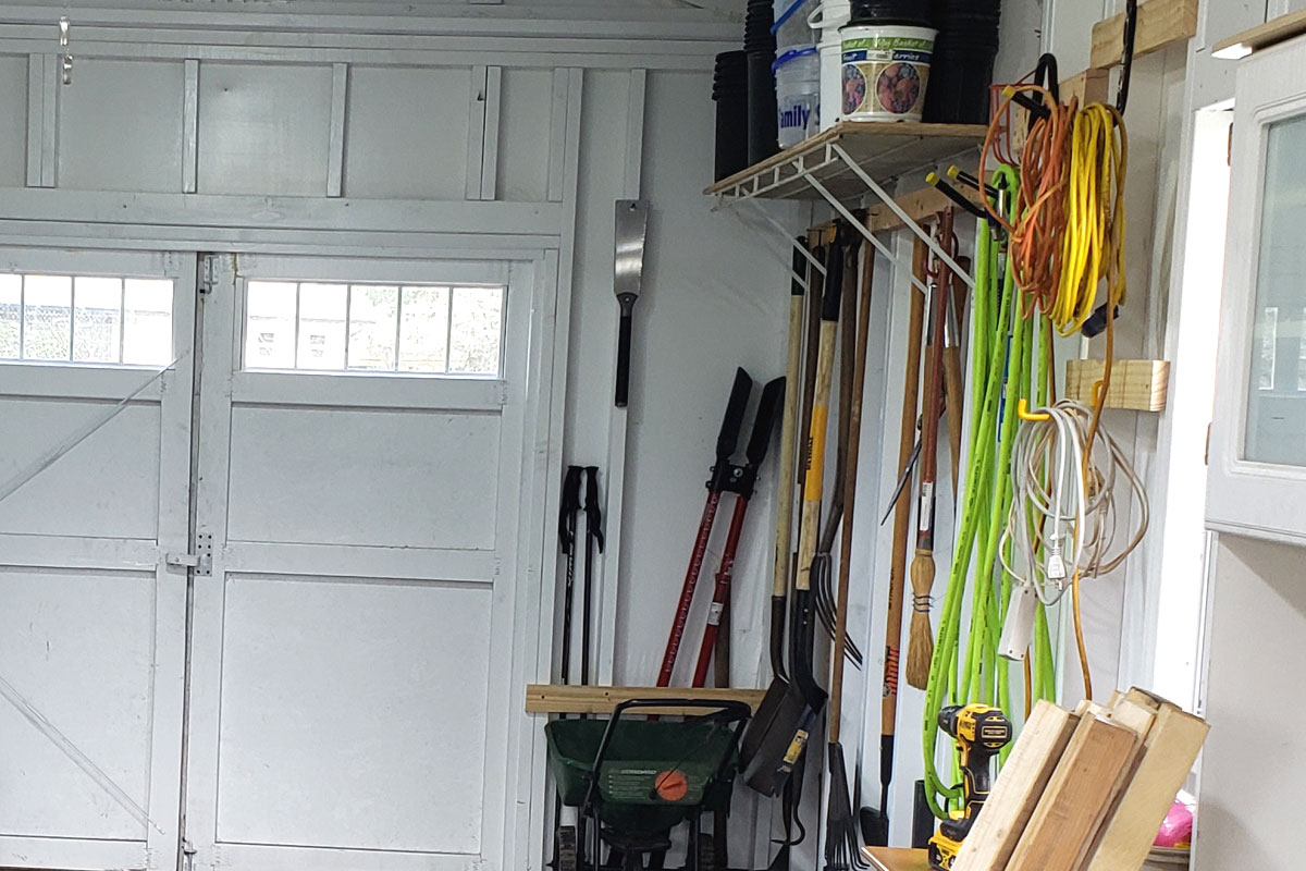 Photo of garden tools hanging on a wall inside a garden shed.
