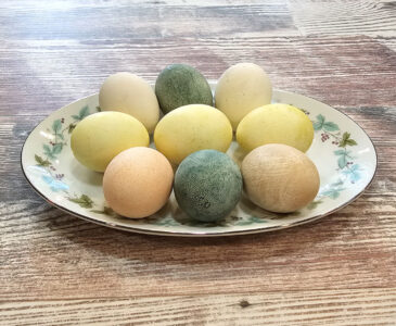 9 Pastel colored Easter eggs on a decorative platter.