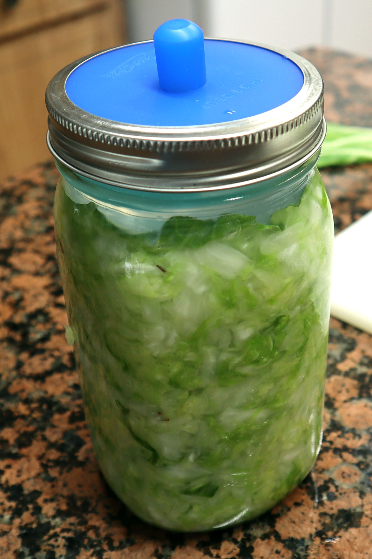 full jar of cabbage in mason jar with attached air lock