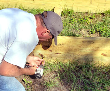 a man screwing boards together to build a raised garden bed