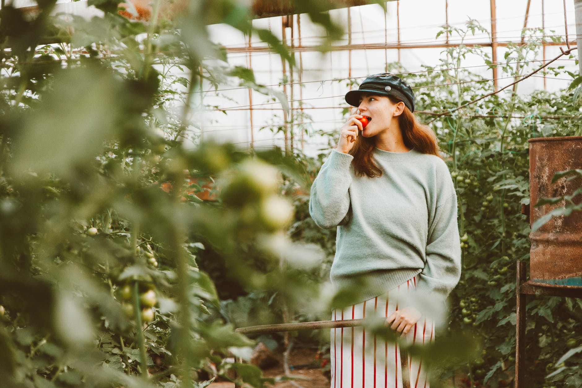 a woman in green long sleeves eating a ripe tomato