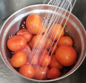 rinsing frozen tomatoes in a colander