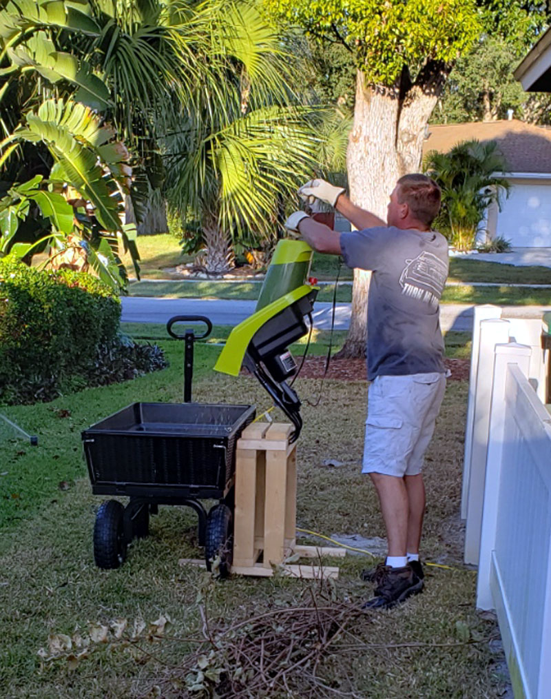 Mike chipping tree branches into a small hand-trailer