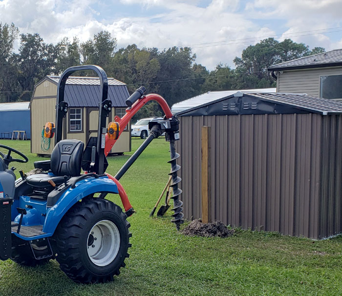 tractor with auger drilling a hole to install a wood post.