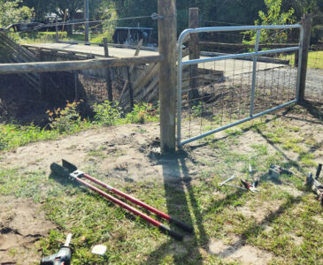 photo of tlls to install a fence post laying on the ground next to a newly-installed H-brace for fencing.