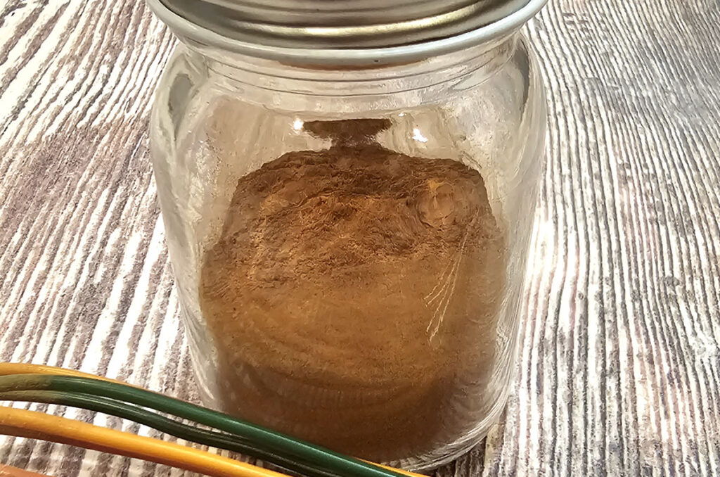 homemade pumpkin spice in a small glass jar with a metal  lid on top.