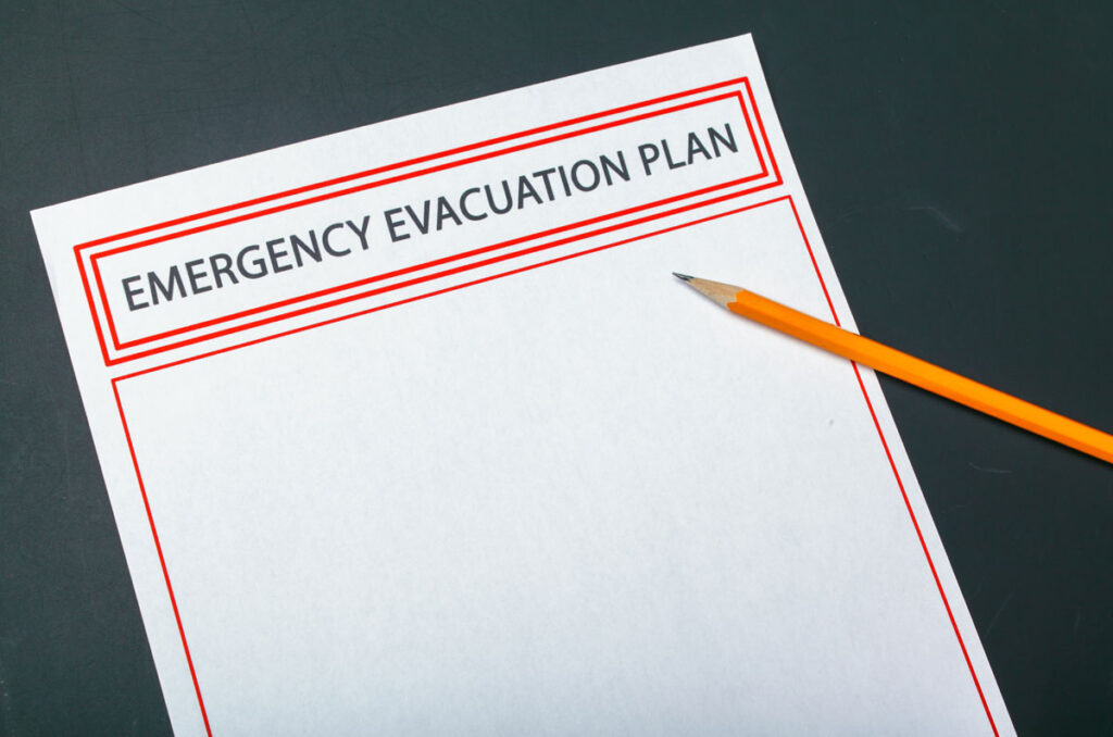 A piece of paper on a dark background with a yellow pencil. The words: Emergency Evacuation Plan are printed across the top. This picture is to emphasize the importance of creating an emergency plan.