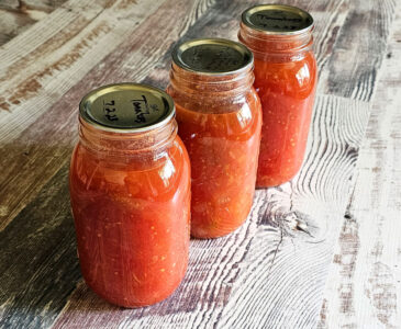 3 Quart jars of canned stewed tomatoes sitting on a countertop.