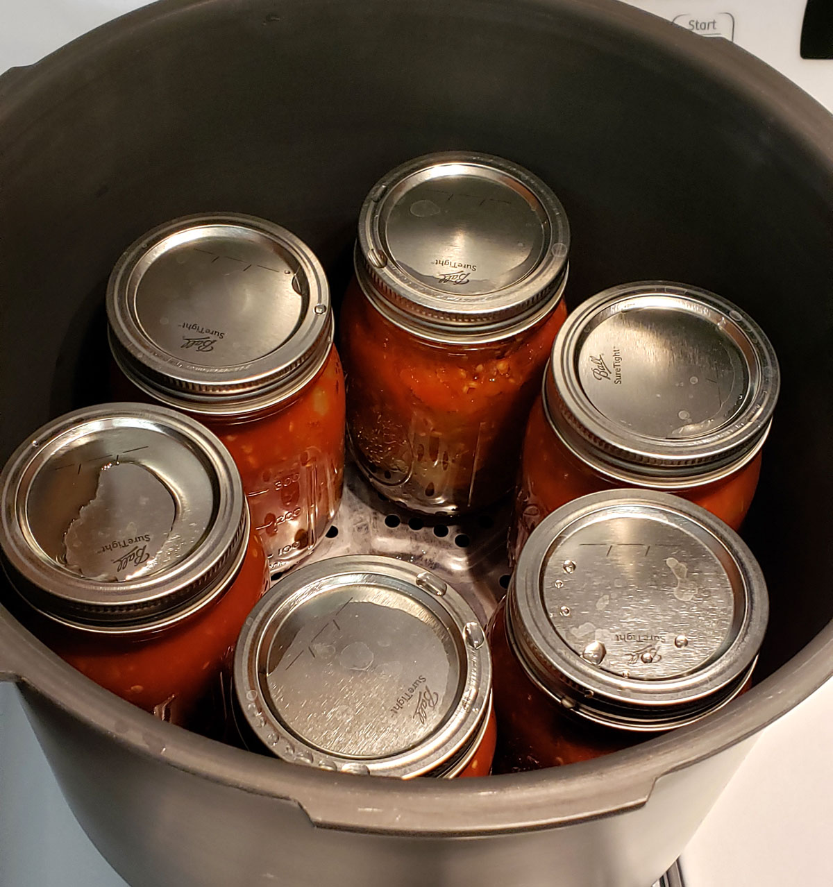 Inside of a pressure canner with 6 pint jars of stewed tomatoes