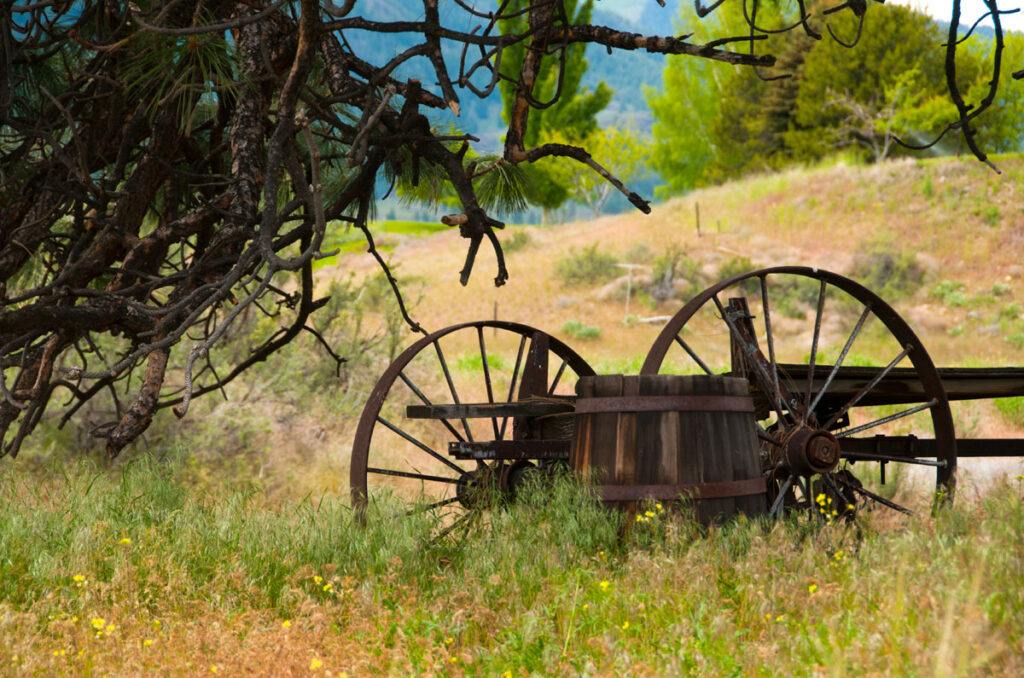 An old wagon and wooden barrel in a western landscape