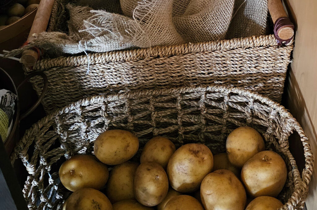 Potatoes in wicker baskets in a kitchen cupboard.