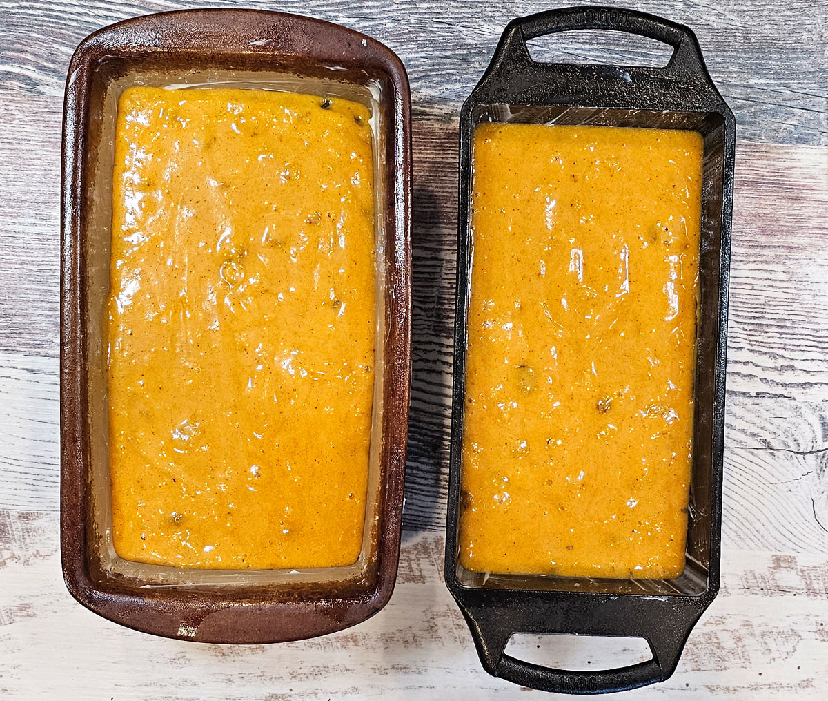 butternut squash quick bread batter in two loaf pans, one is stoneware, the other cast iron.