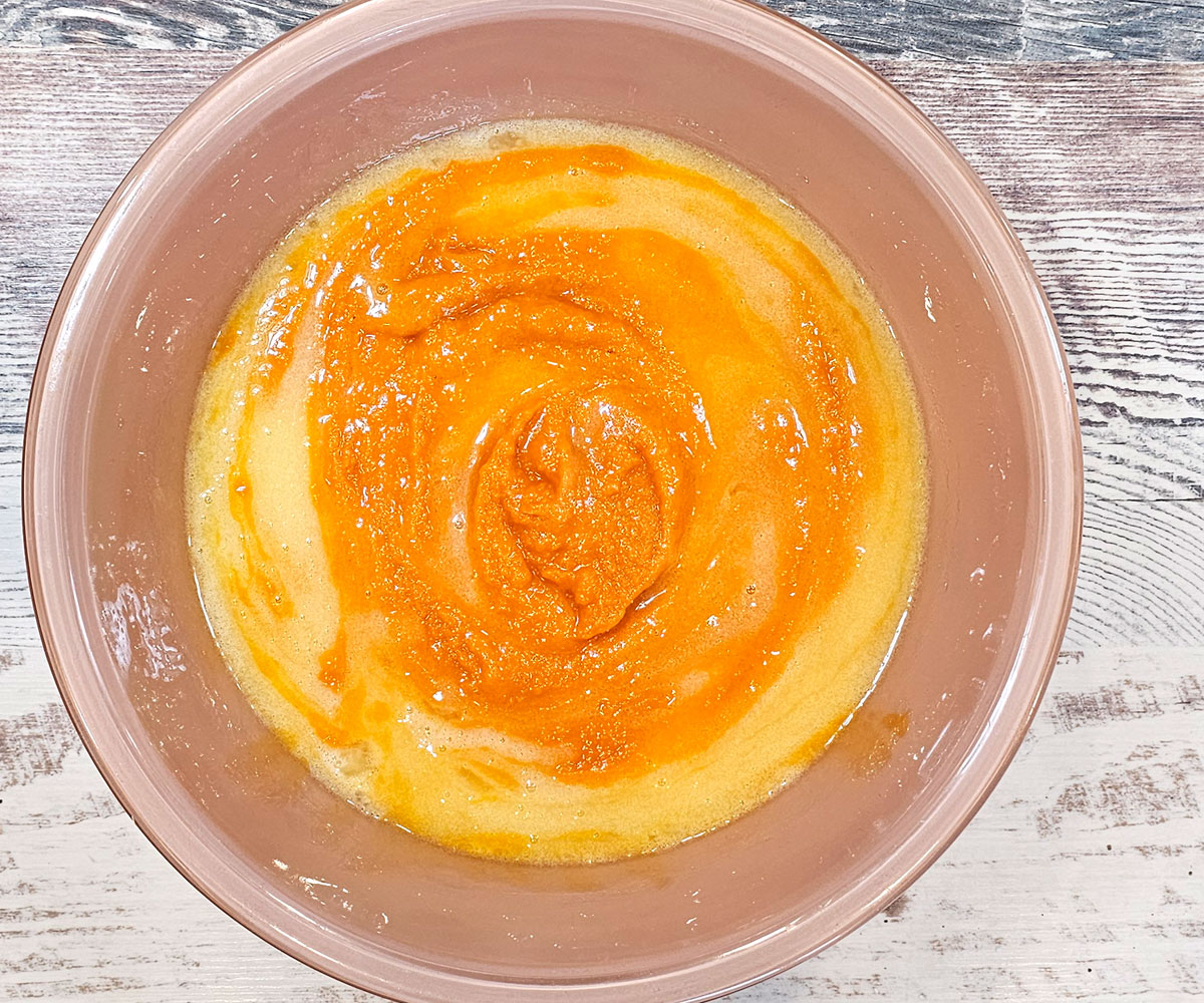 Large mixing bowl with wet ingredients, the squash is slightly stirred in.