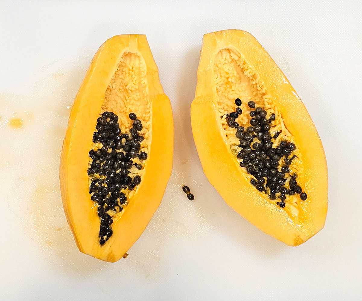 Papaya that is peeled and cut in half lengthwise. The seeds are still inside it.