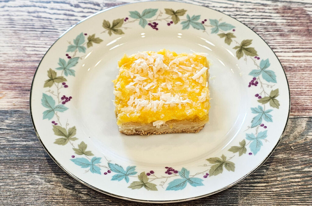 A piece of tropical papaya lemon bar on a round plate on a countertop.