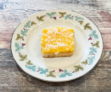 A piece of tropical papaya lemon bar on a round plate on a countertop.