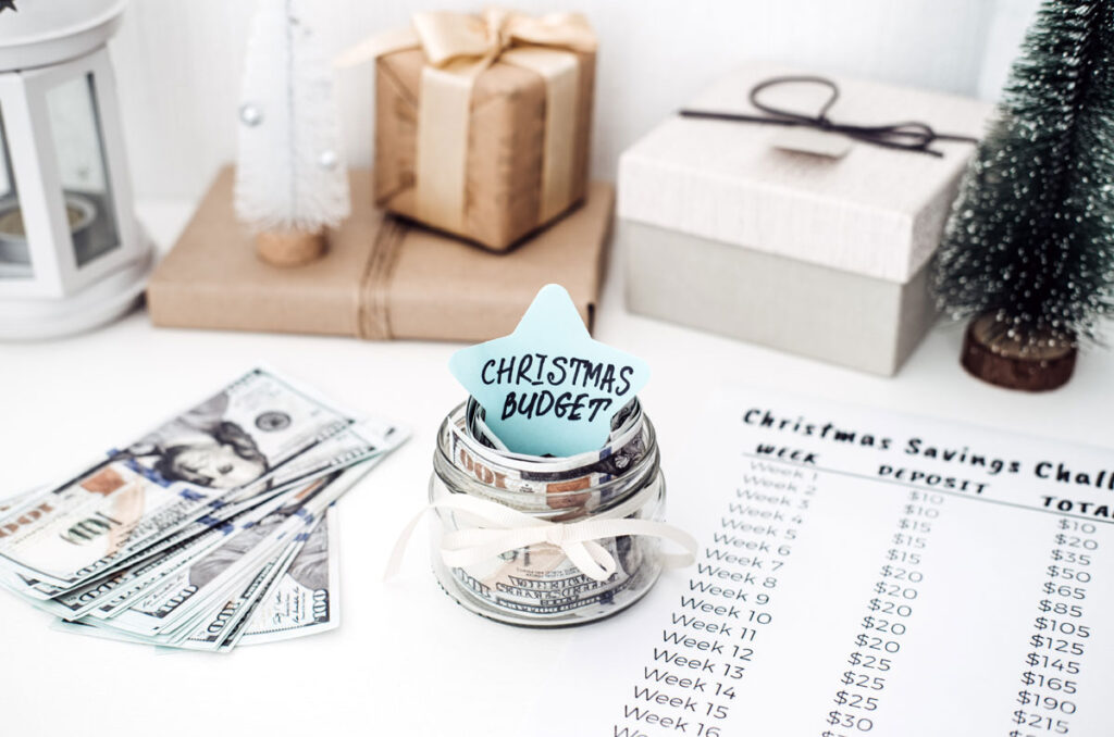 Photo of Christms decorations, cash, and a savings checklist on a table.