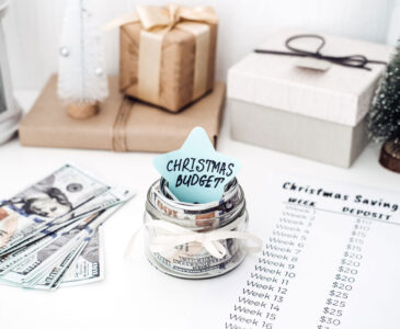 Photo of Christms decorations, cash, and a savings checklist on a table.