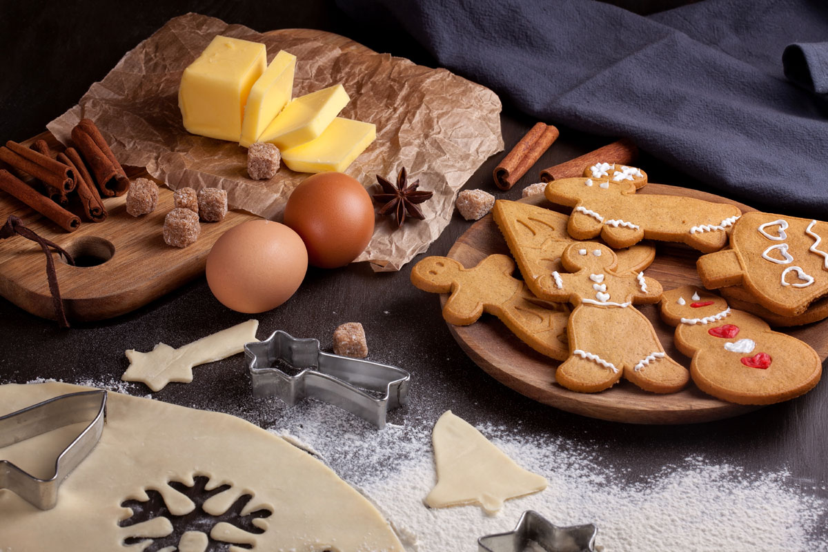 Gingerbread cookies, baking ingredients and a cookie cutter on a table.